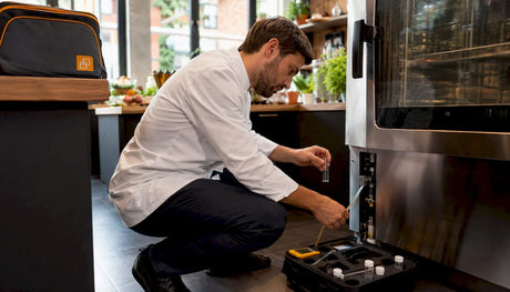 Technician testing water on combi oven in kitchen