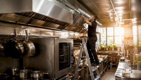 Technician adjusting vent controls over oven canopy