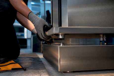 Installer aligning stacked commercial oven feet