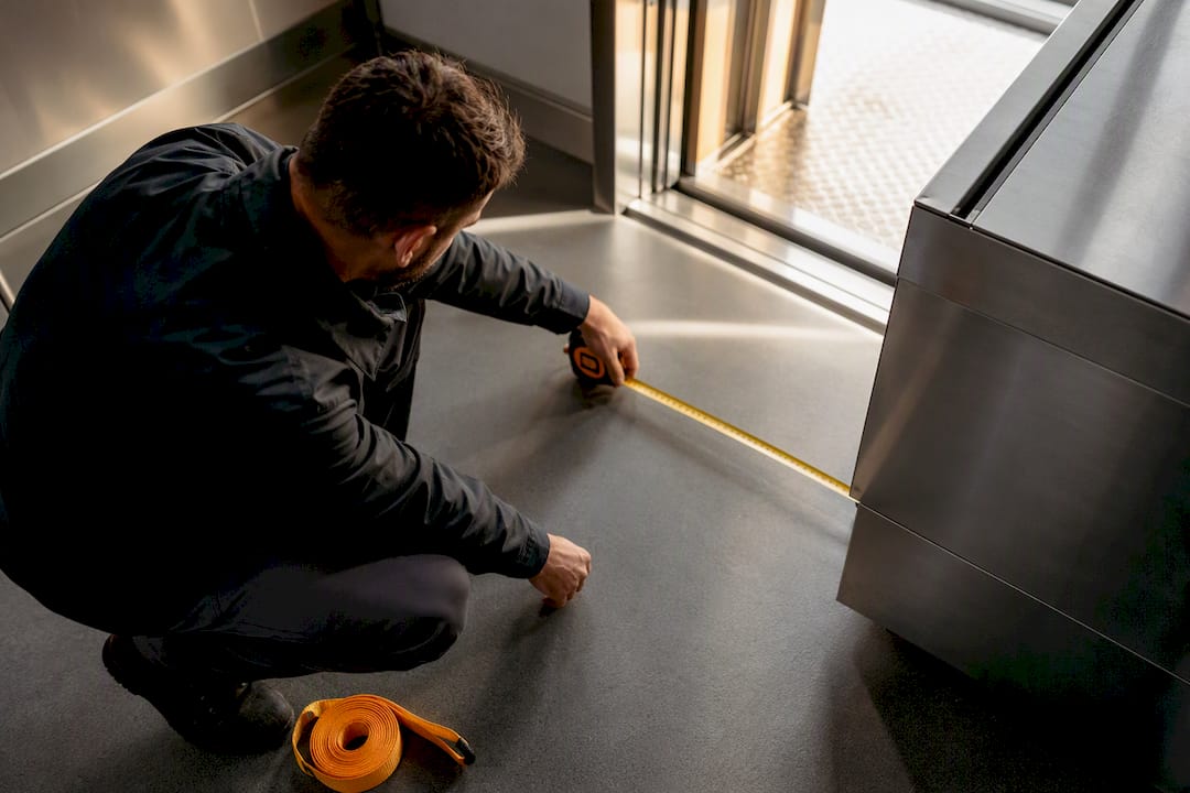 Installer measuring commercial kitchen equipment clearance