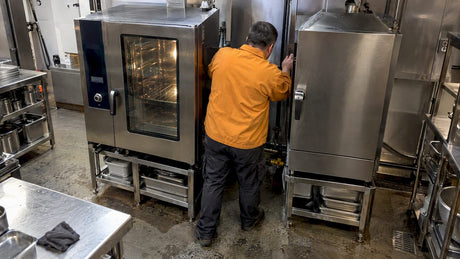 Installer checking space beside two commercial ovens
